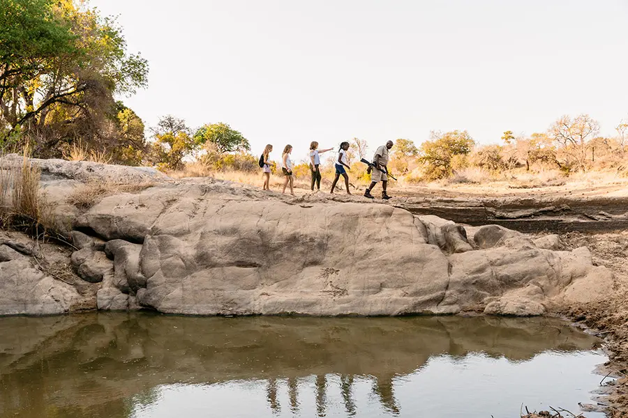 Varias personas cruzan el encuadre de izquierda a derecha en la distancia durante un safari a pie | Go2Africa