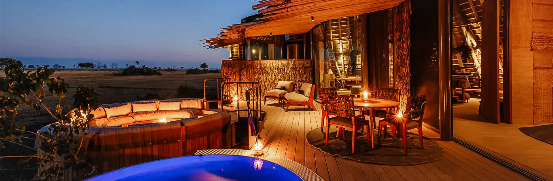 A pool lit up at night surrounded by other warm lighting on the deck of Mombo Camp | Go2Africa