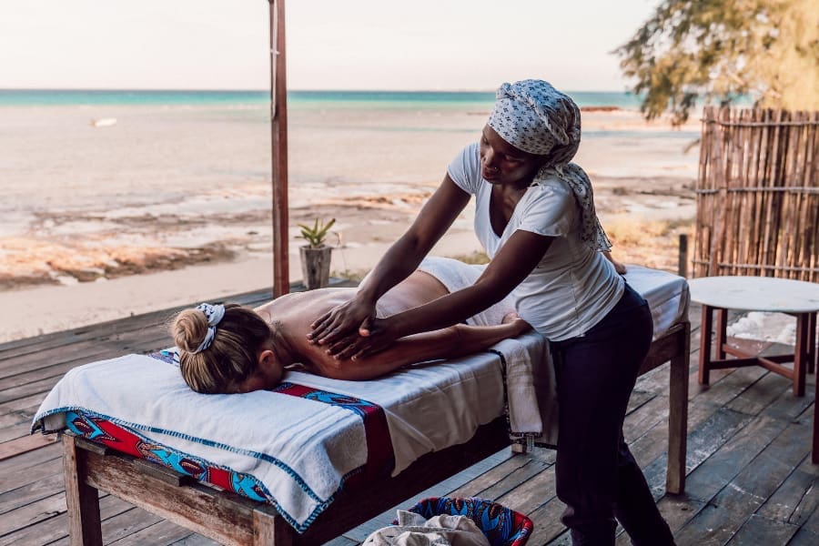 Una mujer en una camilla recibe un tratamiento de masaje de un terapeuta en una terraza al aire libre | Go2Africa