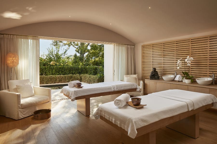 Una hermosa sala de tratamientos de spa con detalles de madera y una gran puerta corredera abierta en el extremo | Go2Africa