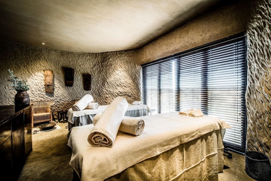 Dos camas de tratamiento en una sala suavemente iluminada de Zannier Omaanda | Go2Africa