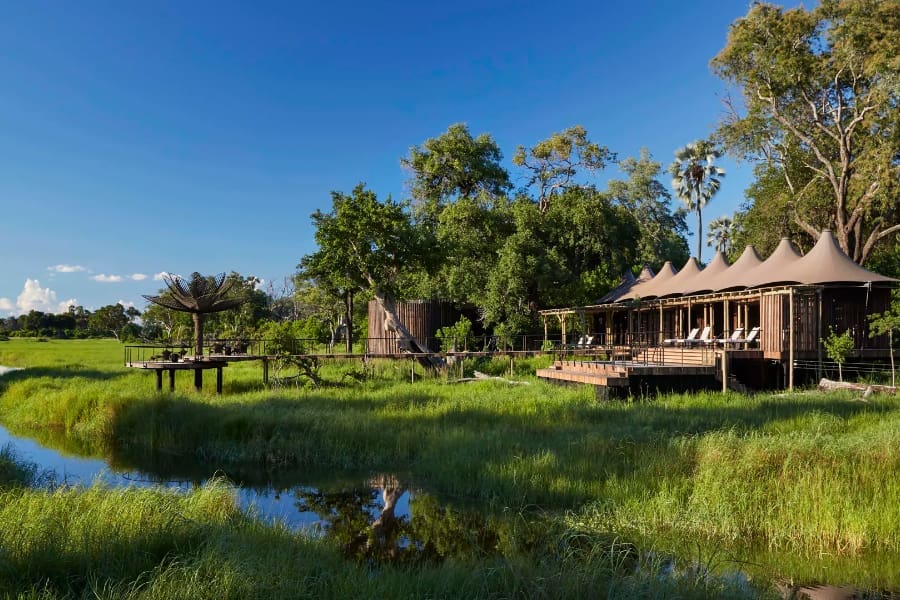 A la derecha hay un edificio de spa con tumbonas, mientras que un puente se extiende sobre los humedales hasta una pequeña estructura separada | Go2Africa