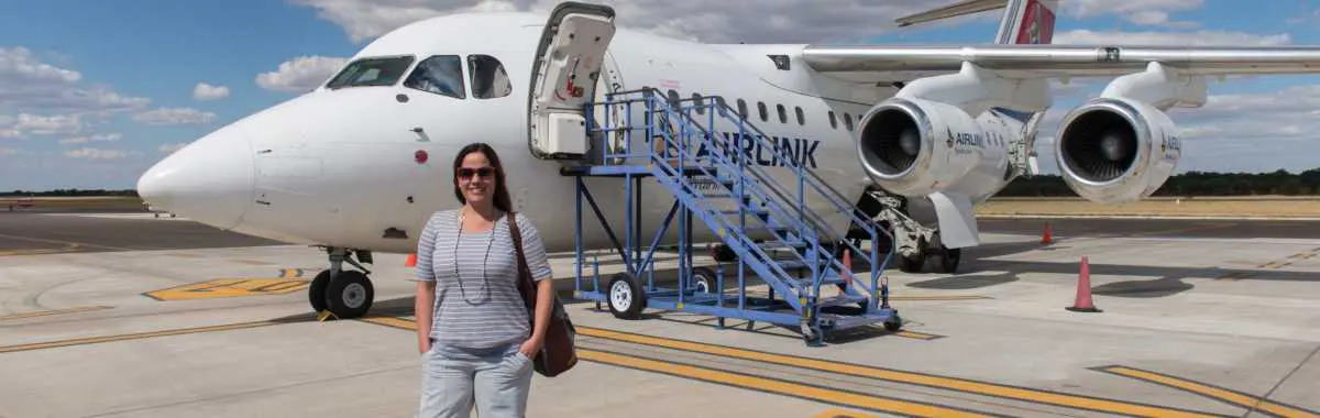 Go2Africa African Safari Expert Liesel van Zyl standing on an airstrip in front of an Airlink aircraft