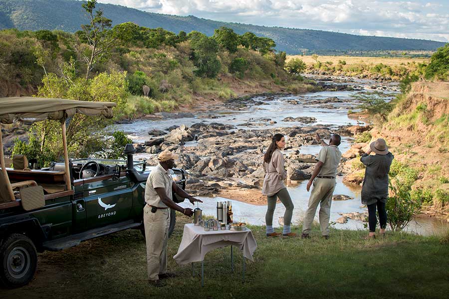 Un vehículo de caza aparcado en el río Mara para una rápida parada de café con los invitados mirando hacia otro lado | Go2Africa