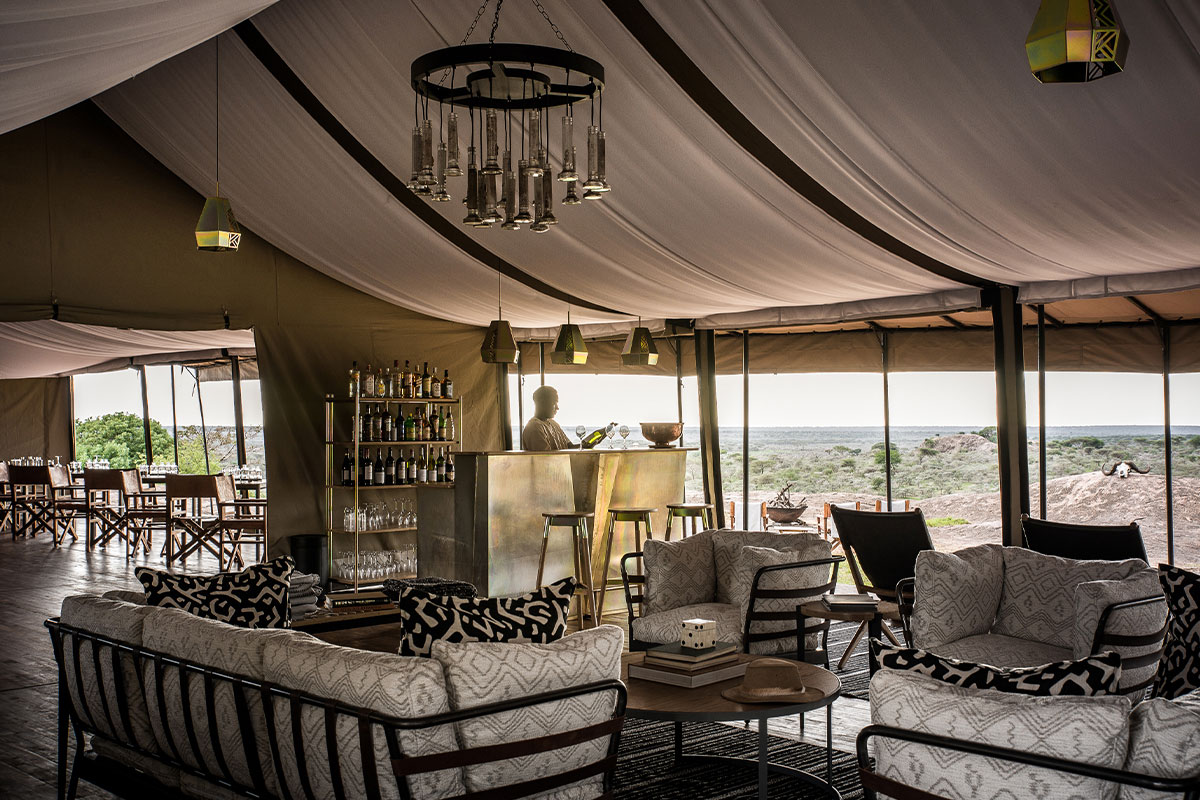 A sitting room complete with bar and chandelier look out over the Serengeti from Sanctuary Kichakani Camp | Go2Africa