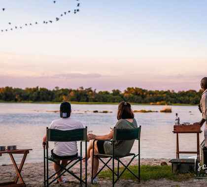Enjoy sundowners as the sun sets on the banks of the river.