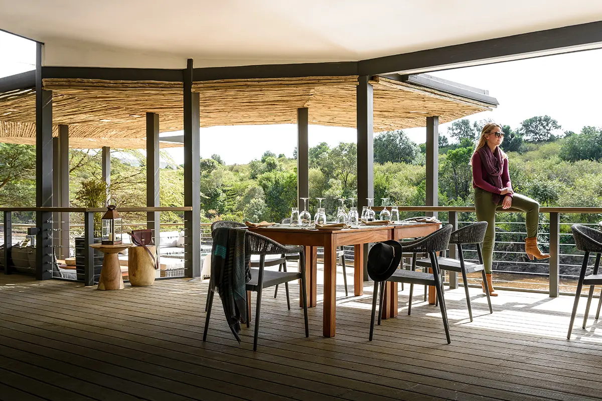 A woman rests on the railing in the dining area of Sanctuary Olonana | Go2Africa
