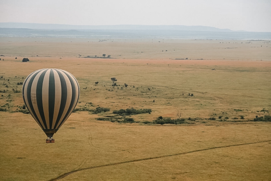 A gold and green hot air balloon floating above Kenyan plains | Go2Africa