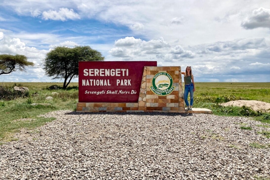 African Safari Expert Monique Lange standing by the Serengeti National Park sign | Go2Africa