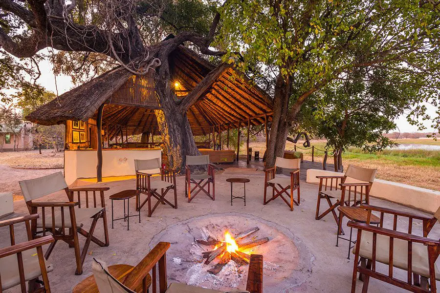 Una reunión rústica al estilo boma alrededor de una hoguera en el campamento Nanzhila Plains | Go2Africa