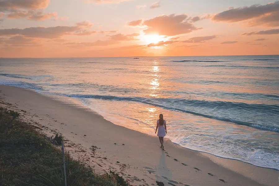 Woman walking on the beach at sunrise in Mozambique.