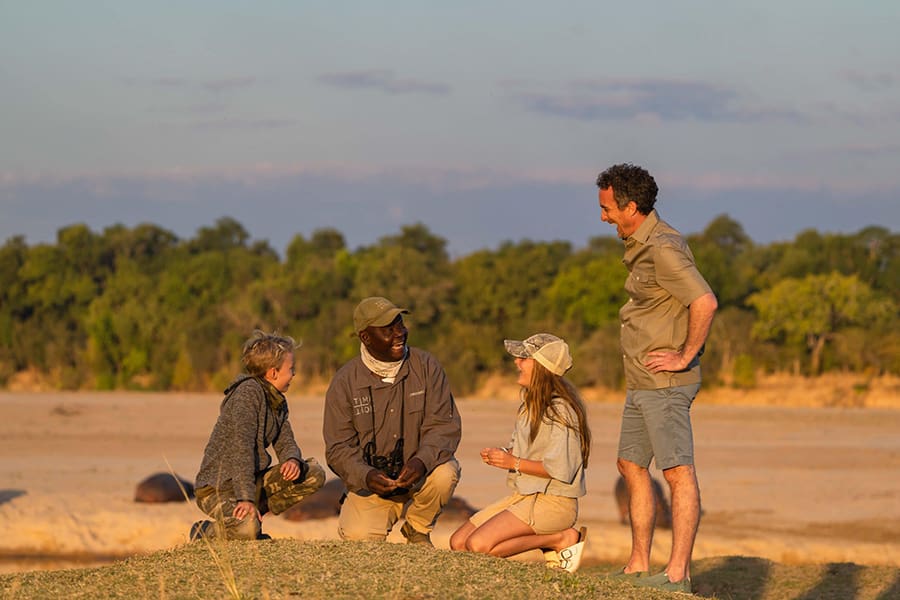La guida di un safari insegna la natura a una famiglia durante un safari a piedi in Zambia.