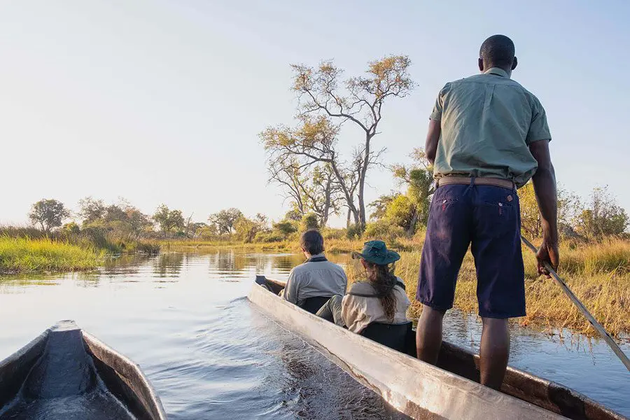 Los huéspedes disfrutan de un paseo en mokoro al mediodía por el delta del Okavango.