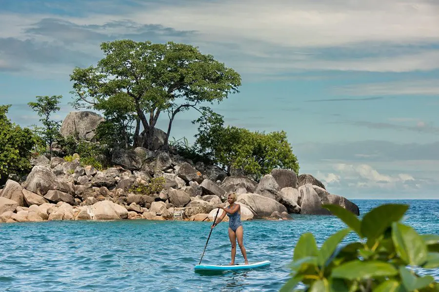 Mujer remando de pie en el lago Malawi, Malawi.