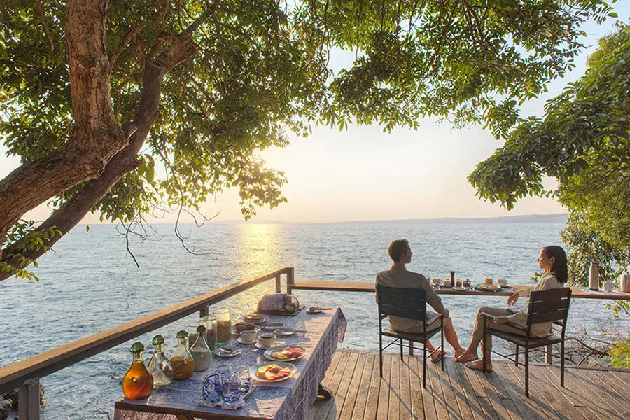 Couple enjoys the view of Lake Victoria on the deck of Rubondo Island Camp in Rubondo Island National Park, Tanzania.