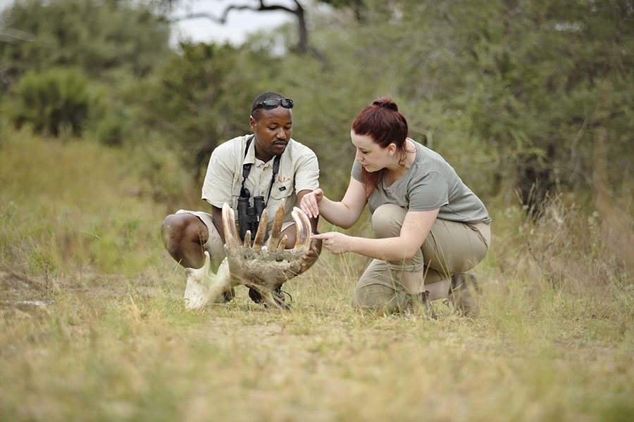 Two people crouching down to look at something found on safari in Nyerere National Park | Go2Africa