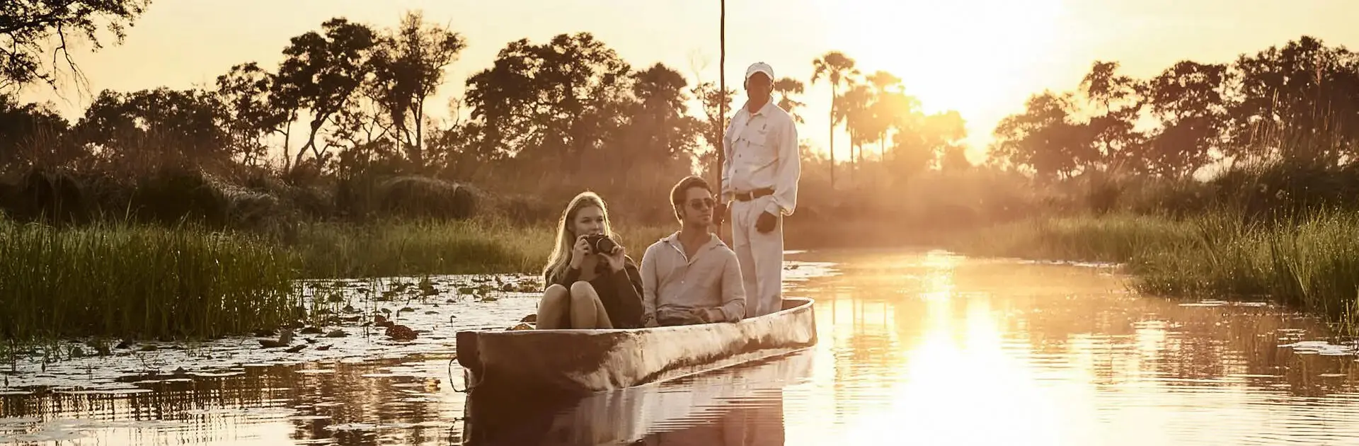 Una pareja en un safari en mokoro con su guía, deslizándose por el río | Go2Africa