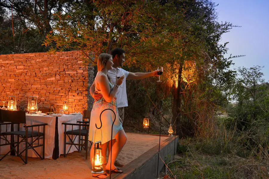 Couple enjoy the view before sitting down for dinner at a safari camp in Africa.