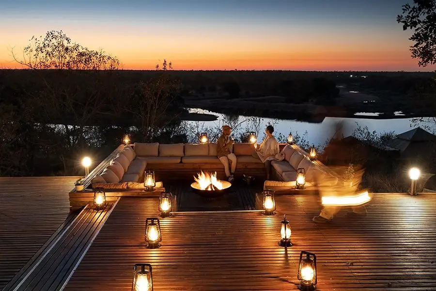 Couple enjoy talking by the fire in a firepit at Simbavati Hilltop Lodge in Africa.