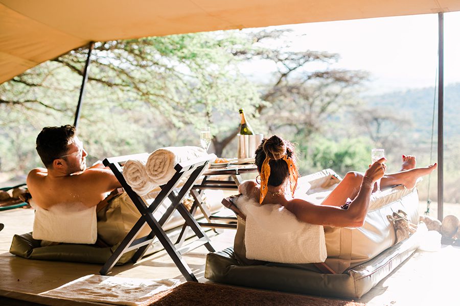 Couple indulging in traditional canvas bush baths at Cottars in Africa.