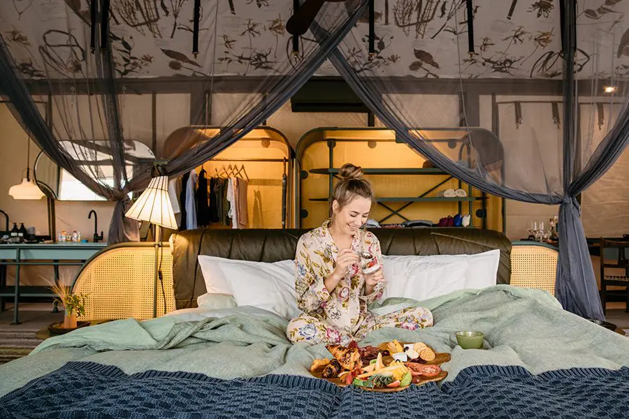 Woman has breakfast in bed at Saseka Tented Camp in Kruger National Park, South Africa.