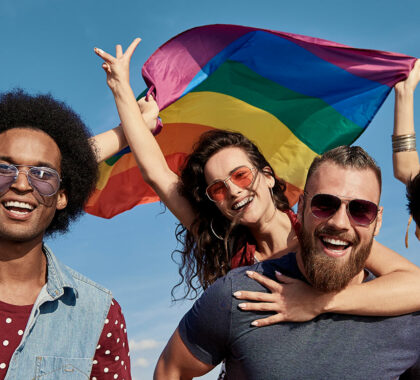 Group of friends holding a gay pride flag.