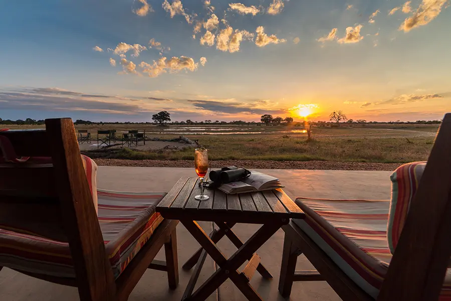 Dos sillas con vistas a una puesta de sol desde Camp Hwange | Go2Africa