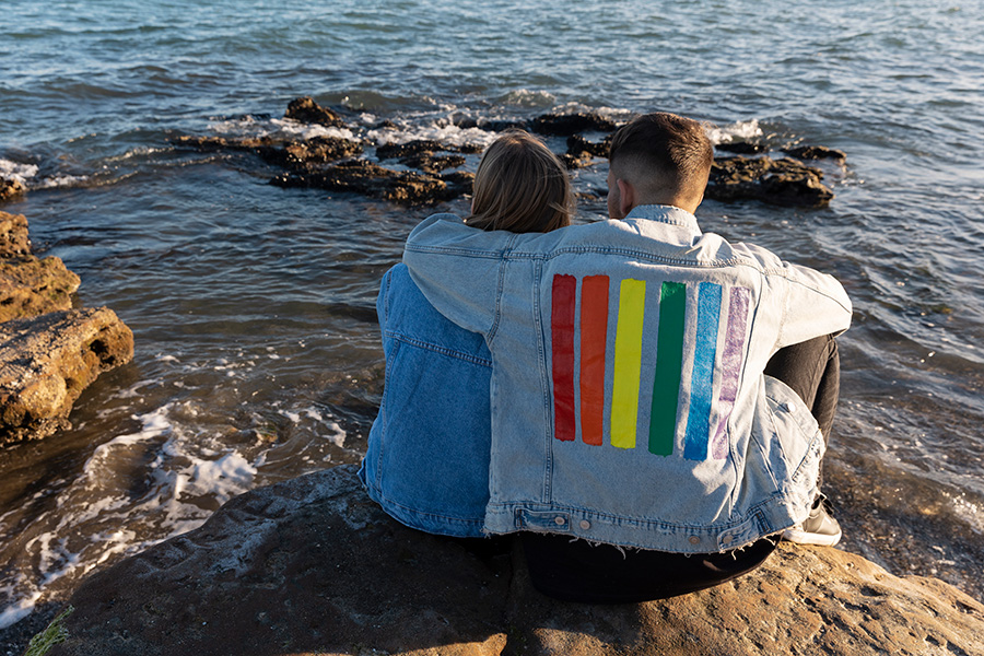 Trans couple spending quality time on the rocks at the ocean.