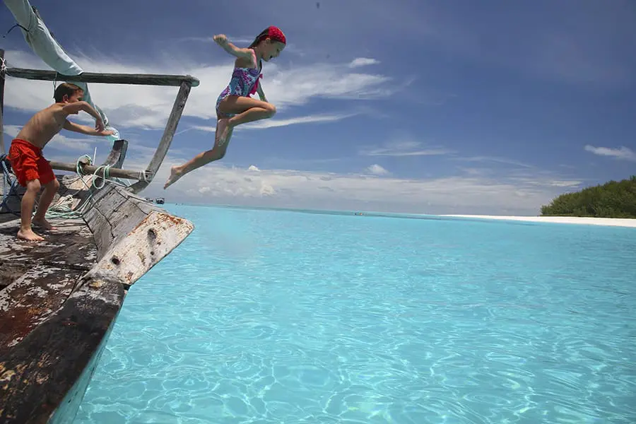 Children jumping off a boat into the ocean off the coast of Zanzibar, Tanzania.