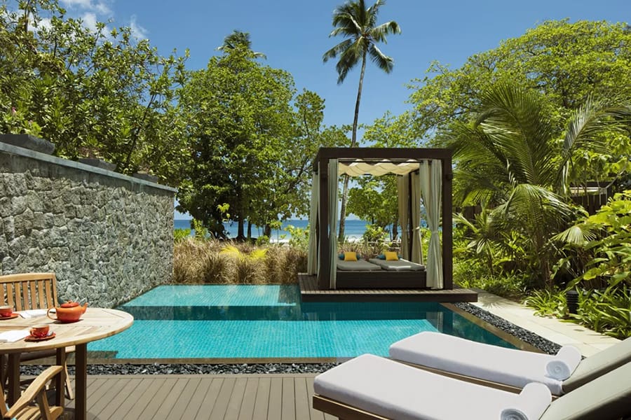 Two pool loungers, a pool, and a covered platform with loungers overlooking tropical gardens and across to the beach | Go2Africa