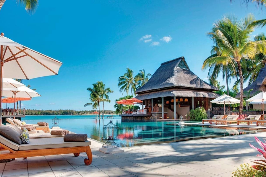 Pool loungers with umbrellas overlooking a beautiful pool and palm trees | Go2Africa