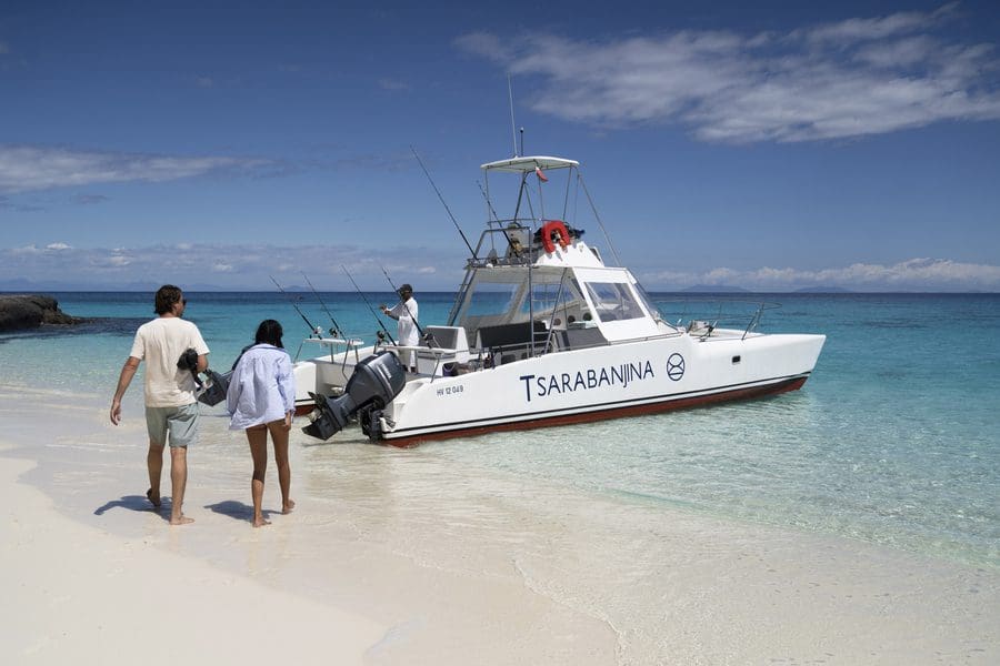 A couple walking across the beach towards a small boat in Madagascar