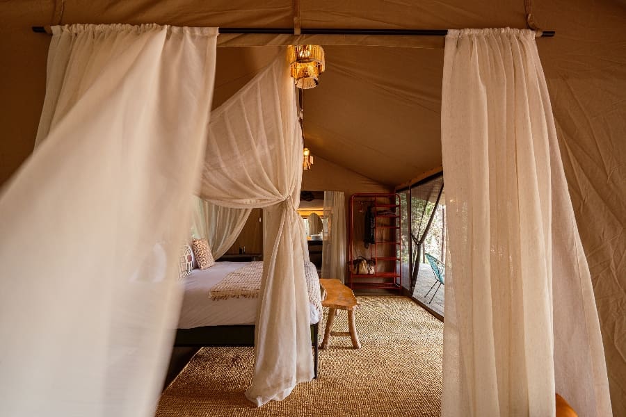 Sweeping gossamer around a 4-poster bed under a tented suite at Emboo Camp | Go2Africa