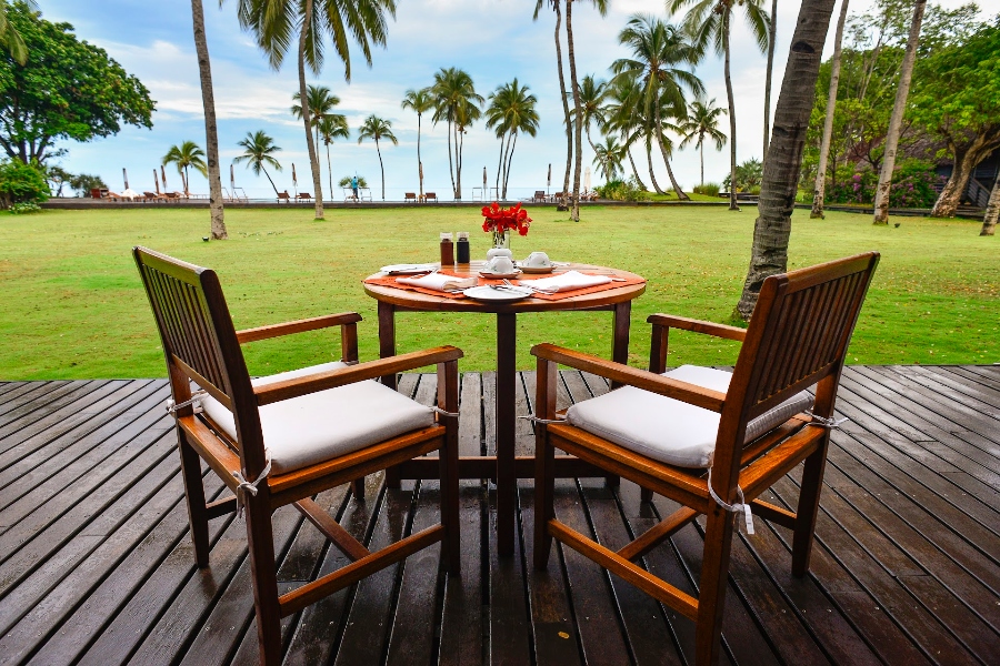 A table and two chairs overlooking grass and palm trees at Anjajavy le Lodge in Madagascar | Go2Africa