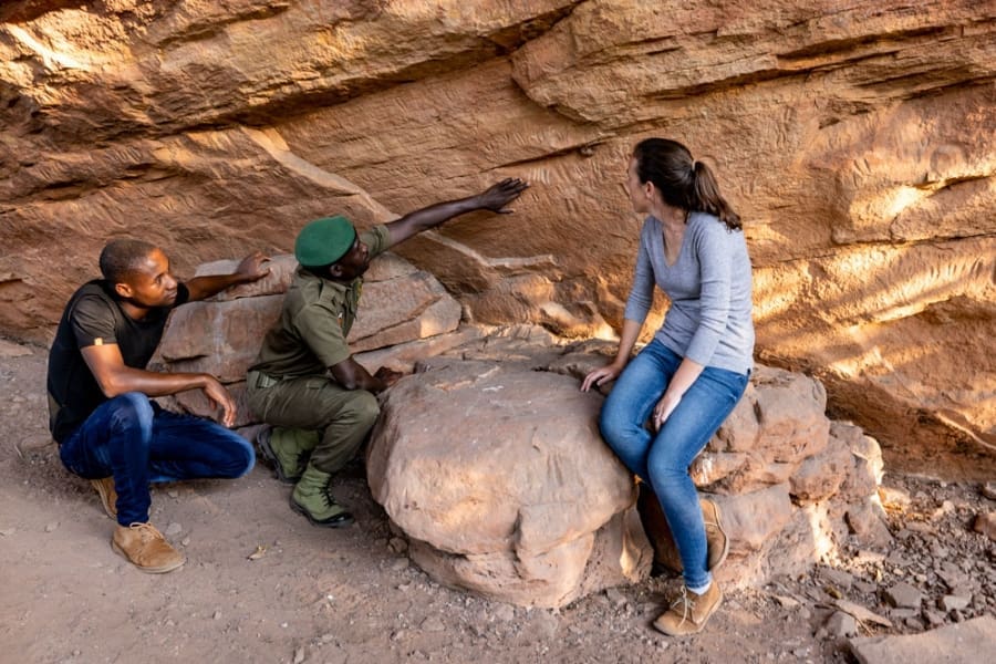 Three people observe rock carvings at Bumbusi National Monument | Go2Africa