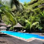 Palapas de paja y una piscina inmaculada rodeada de jardines.