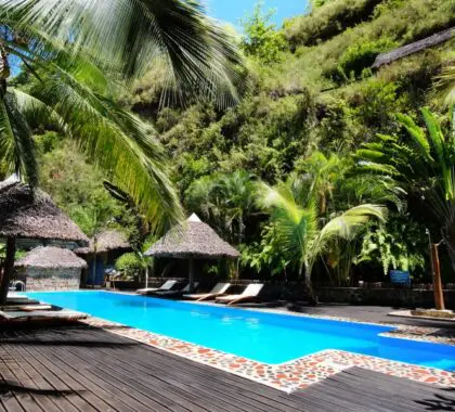 Thatched palapas and a pristine pool surrounded by gardens.