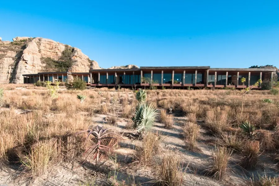 An exterior view of the single story Isalo Rock Lodge in Madagascar pictured with a large rock formation to the left | Go2Africa