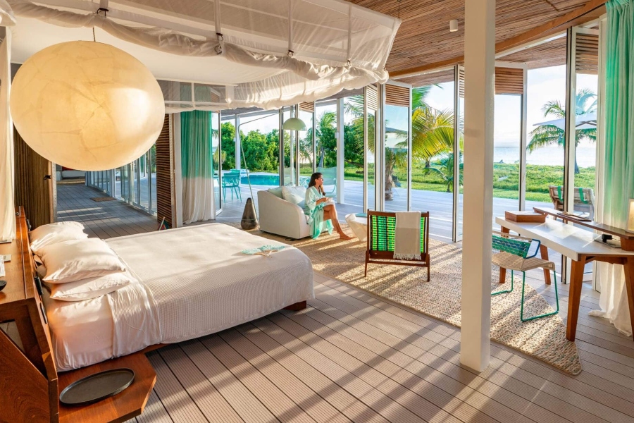 A large bed and spacious seating area with glass sliding doors overlooking a beach in Mauritius | Go2Africa