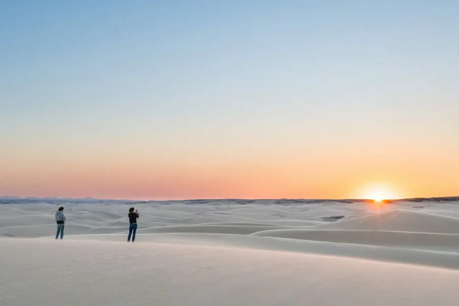 Two people stand on a stretch of sand on Namibia's Skeleton Coast watching the sun set | Go2Africa