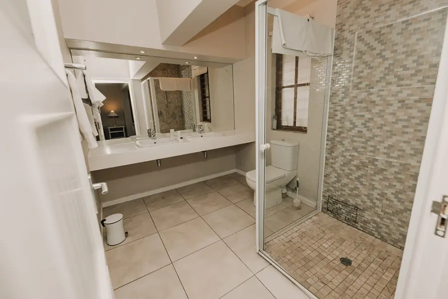 Bathroom boasts double vanity and shower. 