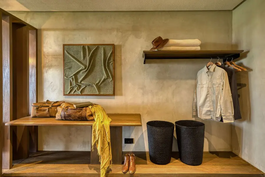 The inside of a dressing room at Serengeti Explorer with two duffel bags, hanging coats, and a pair of boots | Go2Africa