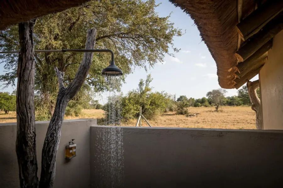 An en-suite bathroom leads to a serene outdoor shower. 