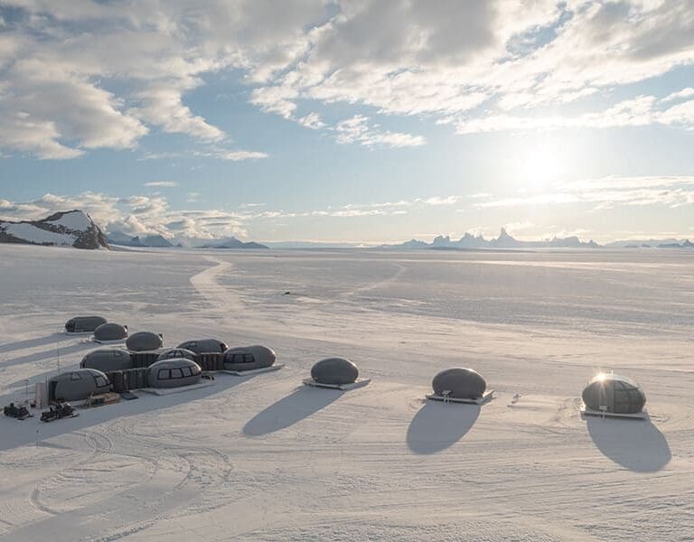 The camp looks out over ice sheets and the rocky-peaked mountains in the distance.