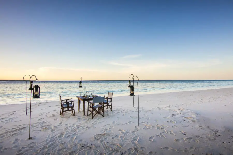 A table is set up for two on the beach of Mnemba Island | Go2Africa