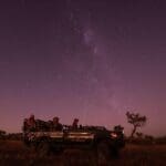 Find yourself enchanted by a stargazing safari in a clearing, where natural light illuminates the silhouettes of bush and trees.