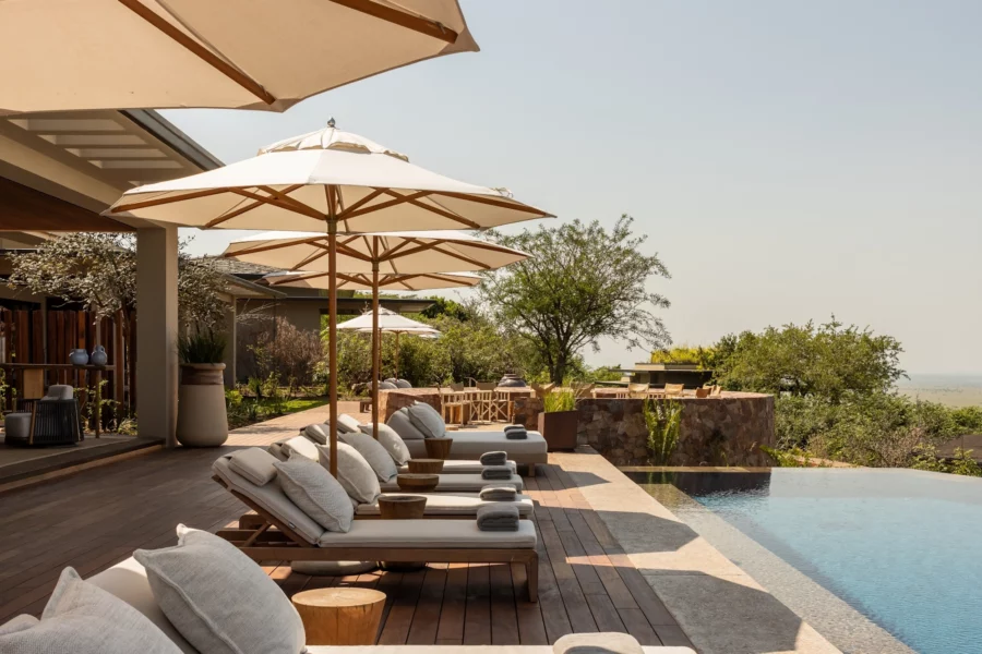 Tumbonas con sombrilla junto a la piscina en un día soleado en Singita Milele.