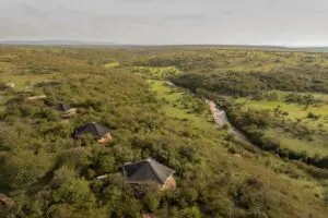 Las tiendas de campaña están escondidas entre los árboles, cerca de un río caudaloso.  