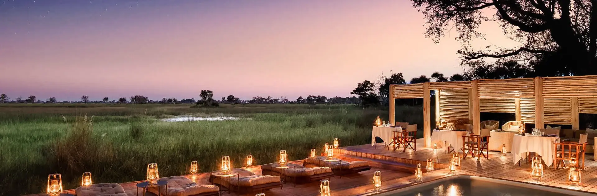 Puesta de sol y luz de velas alrededor de la piscina de un lodge en el delta del Okavango en Botsuana | Go2Africa