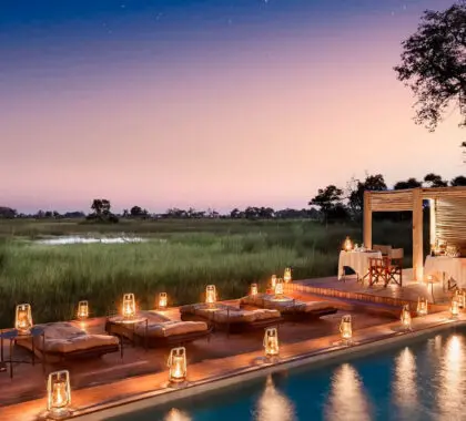 Puesta de sol y luz de velas alrededor de la piscina de un lodge en el delta del Okavango en Botsuana | Go2Africa